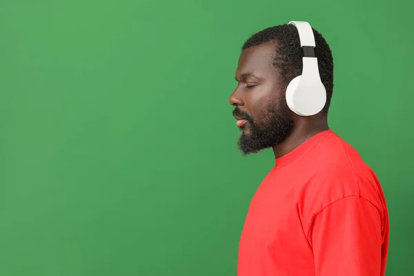 Knappe Afro-Amerikaanse man luisteren naar muziek op kleur achtergrond — Stockfoto