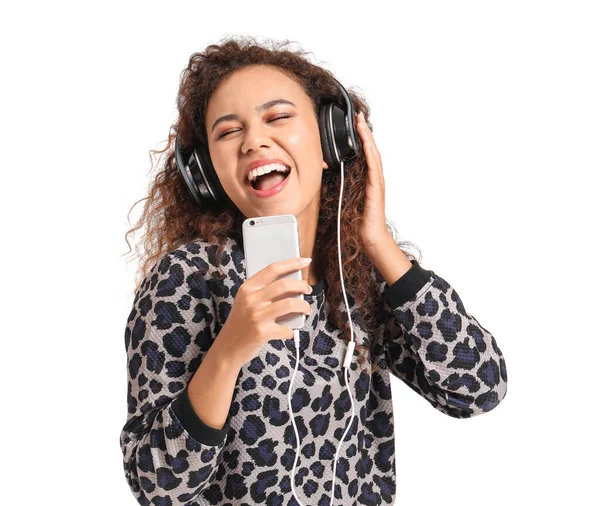 Beautiful African-American woman singing while listening to music on white background — Stock Photo, Image