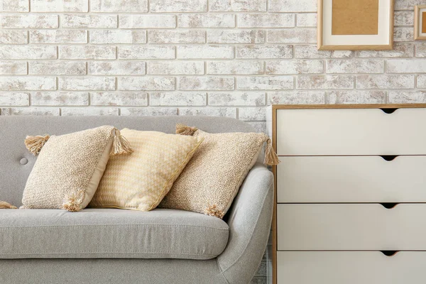 Stylish sofa with chest of drawers and pillows in room — Stock Photo, Image