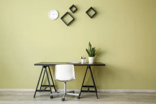 Mesa com cadeira e planta perto da parede de cor — Fotografia de Stock