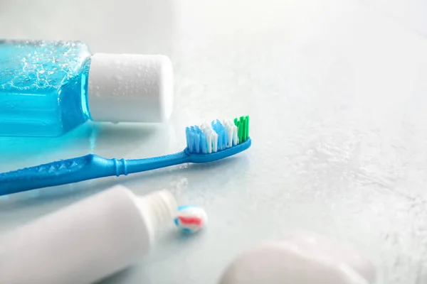 Tooth brush with paste and mouth rinse on white background
