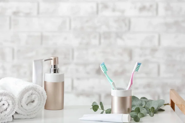 Toothbrushes with paste, towels and soap on table in bathroom — Stock Photo, Image