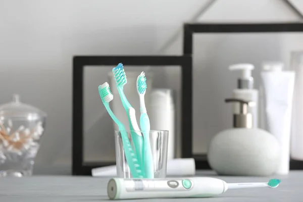 Different toothbrushes on table in bathroom — Stock Photo, Image