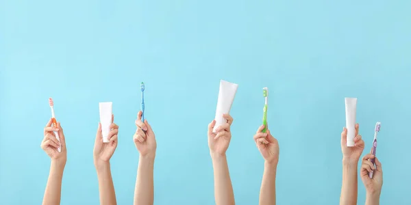 Manos femeninas con cepillos de dientes y pasta sobre fondo de color —  Fotos de Stock