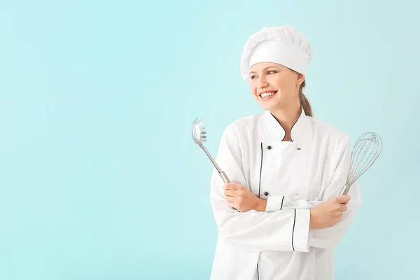 Mooie vrouwelijke chef met keukengerei op lichte achtergrond — Stockfoto