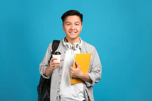 Porträt eines asiatischen Studenten mit einer Tasse Kaffee auf farbigem Hintergrund — Stockfoto