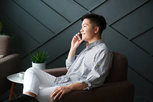 Asijský muž mluví mobilním telefonem doma — Stock fotografie