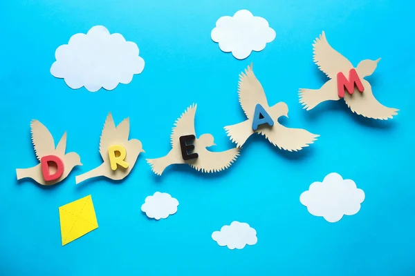 Paper birds with word DREAM and clouds on color background — Stock Photo, Image