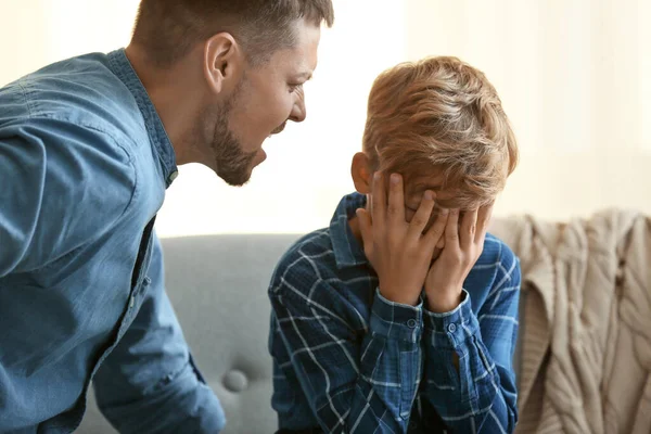 Far skjenner på sønnen sin hjemme. – stockfoto