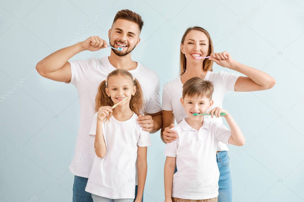 Portrait of family brushing teeth on light background