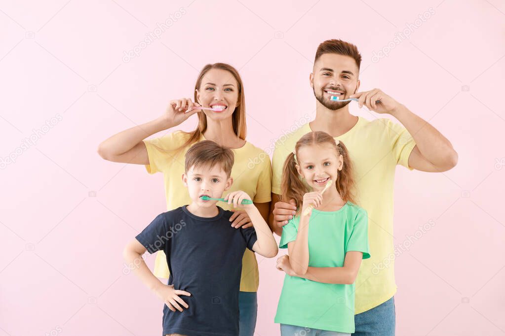 Portrait of family brushing teeth on color background