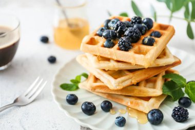Plate with sweet tasty waffles on white table clipart