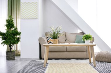 Oturma odasının içinde yeşil bitkiler var.