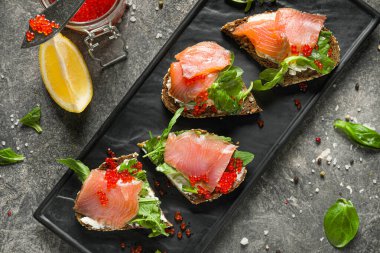 Gri arka planda lezzetli sandviçlerle dolu tabak.