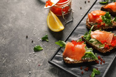 Gri arka planda lezzetli sandviçlerle dolu tabak.