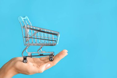 Arka planda boş küçük alışveriş arabası olan bir kadın el.