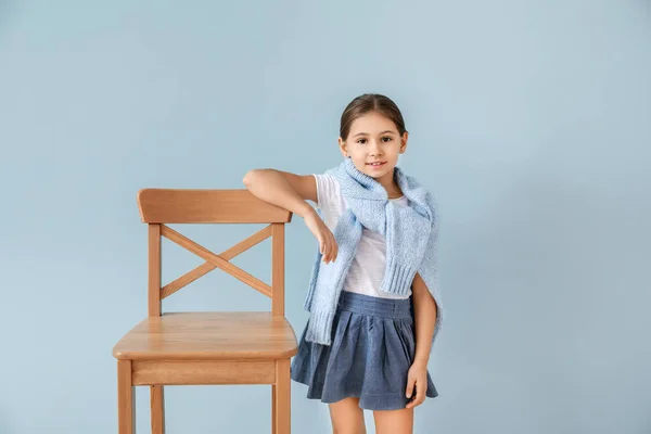 Cute fashionable girl with chair on color background — Stock Photo, Image