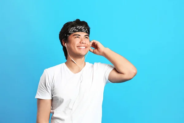 Portrét pohledného asijského muže, jak poslouchá hudbu na barevném pozadí — Stock fotografie