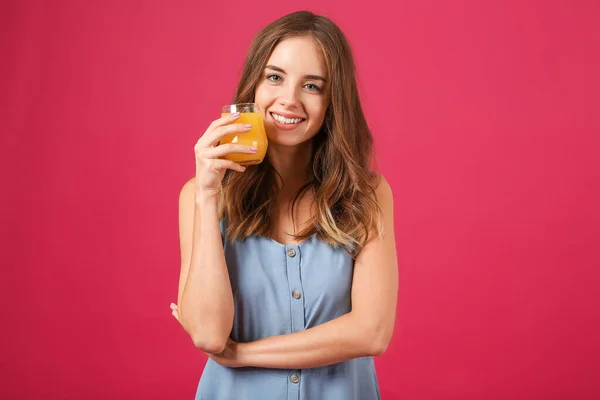 Belle jeune femme avec du jus d'orange sur fond de couleur — Photo