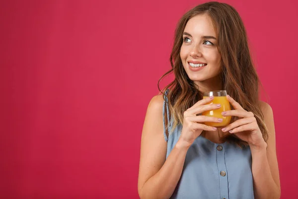 Beautiful young woman with orange juice on color background — Stock Photo, Image