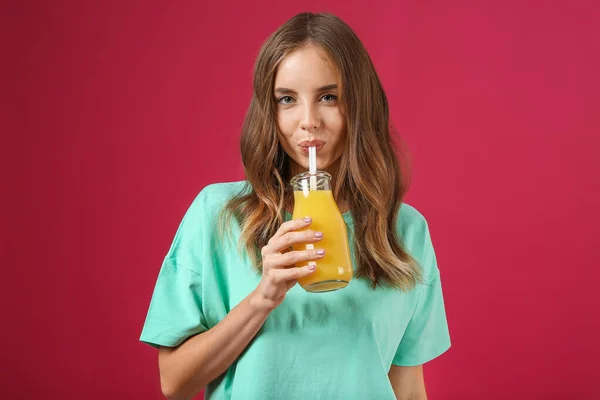 Beautiful young woman with orange juice on color background — Stock Photo, Image