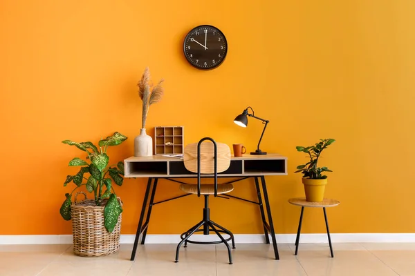 Stylish workplace with green houseplants near color wall — Stock Photo, Image