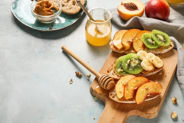 Wooden board with tasty sweet sandwiches on color background — Stock Photo, Image
