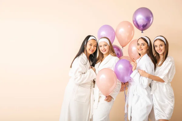 Hermosas mujeres jóvenes en albornoces y con globos de aire sobre fondo claro — Foto de Stock