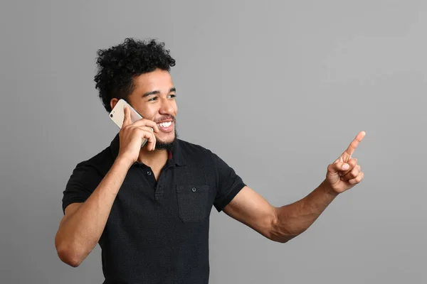 Portret van Afro-Amerikaanse man in gesprek met mobiele telefoon op grijze achtergrond — Stockfoto