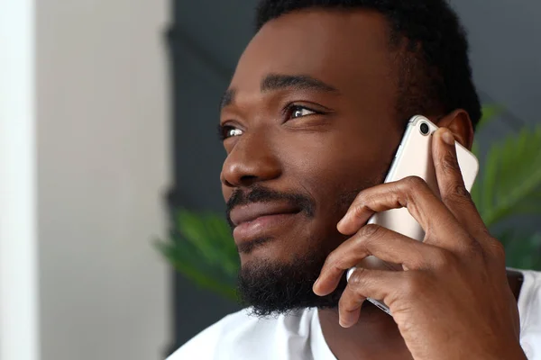 Handsome African-American man talking by mobile phone at home — Stock Photo, Image