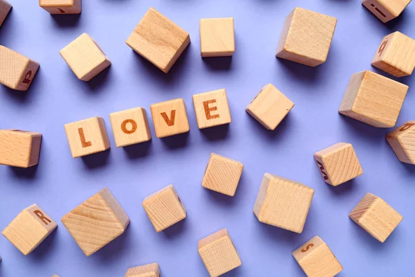 Wooden cubes with text LOVE on color background — Stock Photo, Image