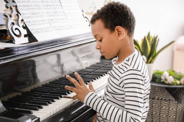 Küçük Afro-Amerikalı çocuk evde piyano çalıyor.
