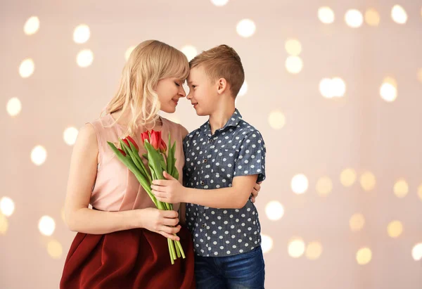 浅色背景的可爱小男孩和他妈妈带着郁金香花束的画像 — 图库照片