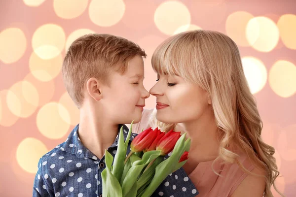 Portrait of cute little boy and his mother with tulip bouquet on color background — Stock Photo, Image
