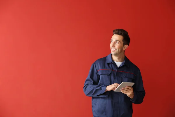 Mecánico de coche masculino con tableta de ordenador sobre fondo de color — Foto de Stock