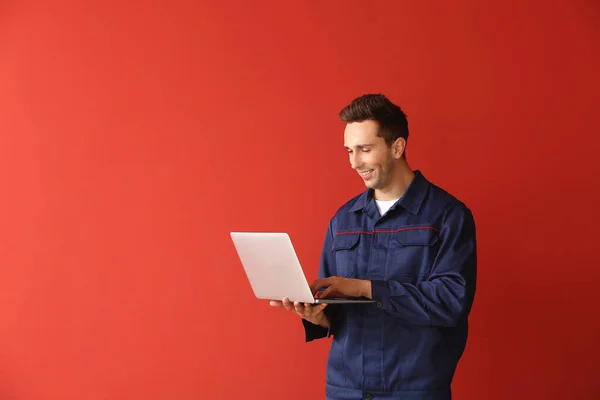 Muž auto mechanik s notebookem na barevném pozadí — Stock fotografie