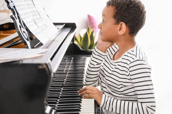 En liten afroamerikansk pojke som spelar flygel hemma. — Stockfoto