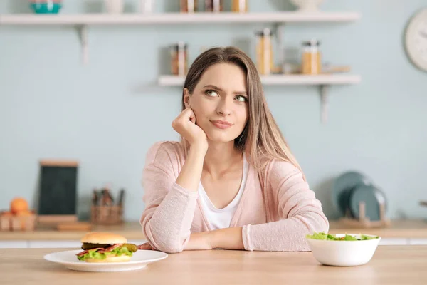 Mujer elegir entre alimentos saludables y poco saludables en la cocina. Concepto de dieta —  Fotos de Stock