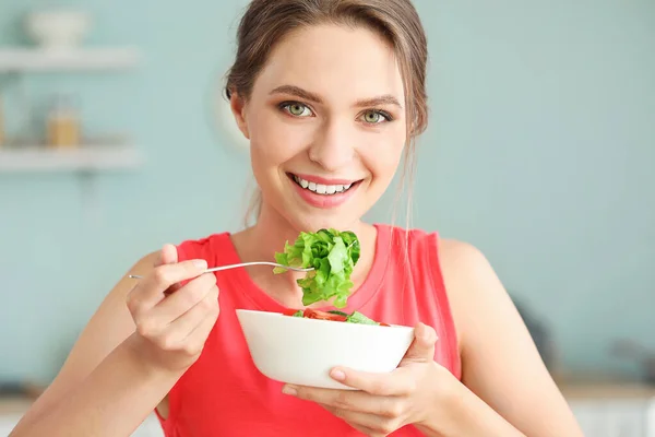 Jeune femme mangeant une salade de légumes saine dans la cuisine. Concept de régime alimentaire — Photo