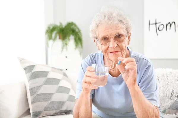 Elderly woman taking pill at home — Stock Photo, Image