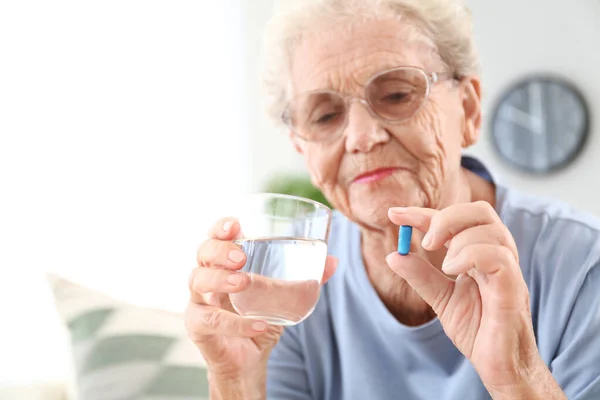 Elderly woman taking pill at home — Stock Photo, Image