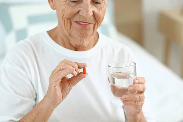 Пожилая женщина принимает лекарства дома — стоковое фото