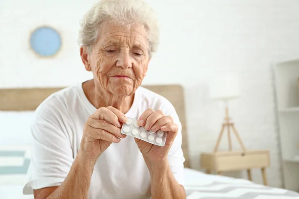Elderly woman with pills at home — Stock Photo, Image