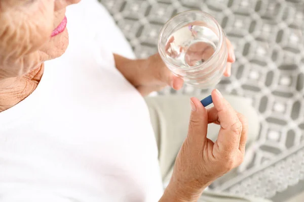 Elderly woman taking pill at home, closeup — Stock Photo, Image