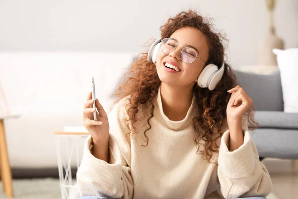 Beautiful African-American woman listening to music at home — Stock Photo, Image