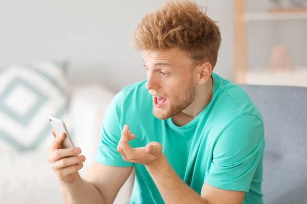 Porträtt av förvånad man med mobiltelefon hemma — Stockfoto