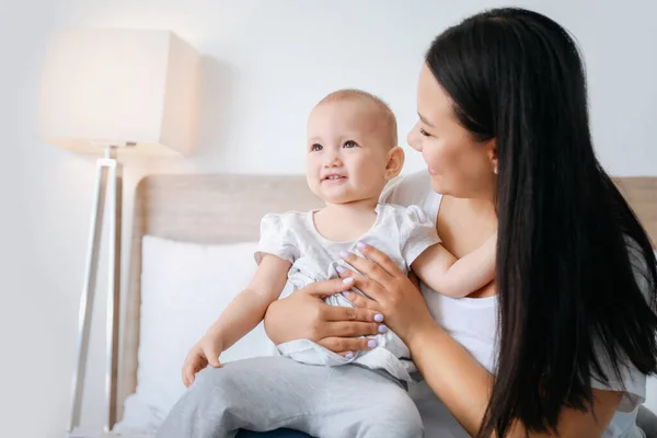 Asian mother and cute little baby sitting on bed — Stock Photo, Image