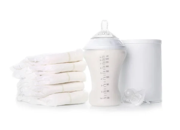 Fles melk voor baby met pot, fopspeen en luiers op witte achtergrond — Stockfoto