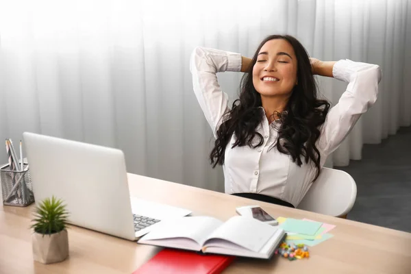 Beautiful Asian woman relaxing in office — Stock Photo, Image