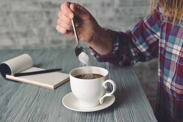 Frau gießt Zucker in Tasse mit heißem Kaffee am Tisch — Stockfoto